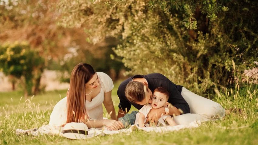 A happy family having a picnic in a lush green park setting during the day.